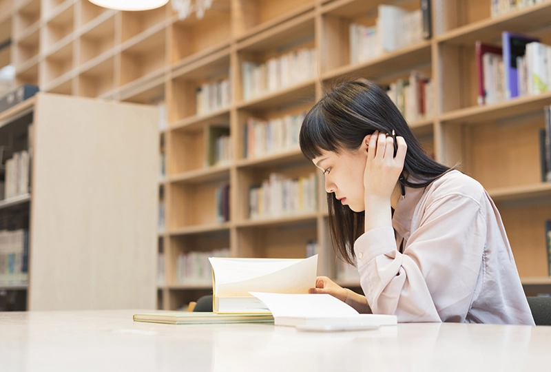 図書館で勉強する女子大学生の写真